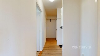 Úzká chodba s parketovou podlahou, bílými stěnami a moderním osvětlením, poskytuje přístup k dalším místnostem v bytě