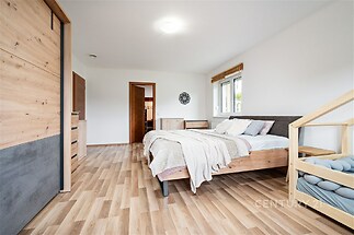 Prostorná ložnice s parketovou podlahou, moderní vestavěné skříně, světlé stěny a dřevěný nábytek, ideální pro rodinný domov.