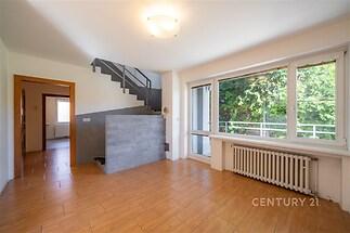 Světlý obývací pokoj s velkými okny, parketovou podlahou a moderními detaily. Výhled na zeleň, otevřená dispozice, ideální pro rodiny.