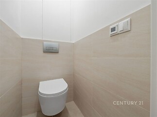 Moderní toaleta s keramickými obklady, minimalistický design a světlé neutrální tóny vytvářejí elegantní a čistý vzhled.