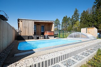 Zahrada s venkovním bazénem, dřevěnou terasou a moderní vířivkou poskytuje relaxaci v přírodním prostředí s kvalitním oplocením pro soukromí.