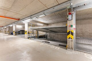 Podzemní garáž s moderními parkovacími systémy, betonovou povrchovou úpravou a dostatkem osvětlení, ideální pro bezpečné parkování.