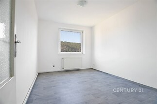 Světlý pokoj s moderními světlými podlahami, plastové okno s výhledem do přírody, čerstvě vymalované stěny, rekonstruovaný prostor.