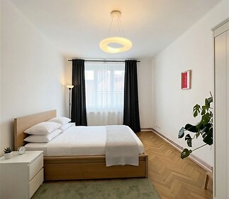 Prostorná ložnice s parketovou podlahou, velkým oknem.