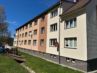 Fasáda bytového domu s novou omítkou, plastová okna a satelitní anténa, situovaný v klidné části na okraji města.