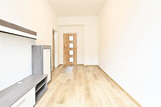 Světlý obývací pokoj s parketovou podlahou a moderním nábytkem, dveře z přírodního dřeva, prostor vhodný pro rekonstrukci nebo úpravy.