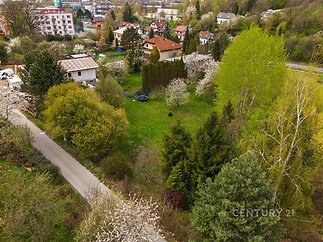 Prázdná zahrada s trávníkem obklopená vzrostlými stromy, vhodná pro výstavbu. Klidná lokalita v blízkosti rezidenční zástavby.