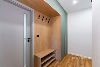 Vstupní chodba s dřevěnou vestavěnou skříní, moderní design, vinylová podlaha, praktické úložné prostory, světlé osvětlení