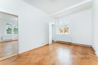 Světlý pokoj s parketovou podlahou a velkými okny, bílá stěna, moderní interiér.