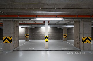 Prázdné parkovací stání s betonovou podlahou, sloupy a moderním osvětlením, ideální pro bezpečné uskladnění automobilu v podzemní garáži.