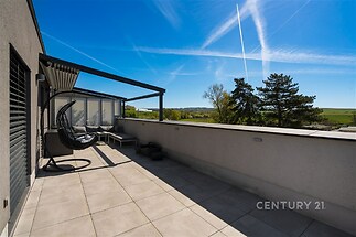 Prostorná terasa s moderní dlažbou a pergolou nabízí panoramatický výhled na krajinu, ideální pro venkovní relaxaci a zábavu.
