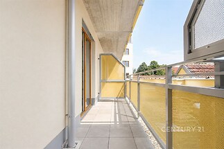 Prostorný balkon s dlažbou, moderními zábradlím a výhledem na městskou krajinu nabízí příjemné venkovní posezení.