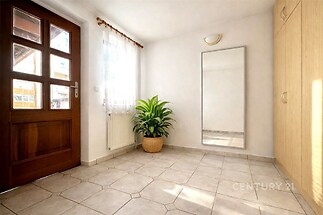 Vstupní hala s dlažbou, velkým zrcadlem a vestavěnými skříněmi, světlá se dřevěnými dveřmi a oknem pro přirozené osvětlení.