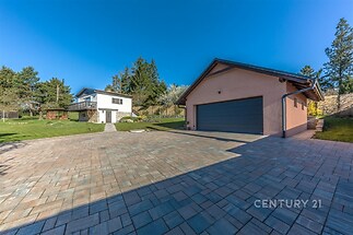 Prostorný dlážděný dvůr s moderní garáží a velkou zahradou, která nabízí klidné prostředí a dostatek soukromí.