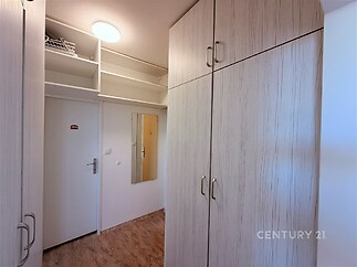 Chodba s vestavěnými skříněmi, moderní laminátová podlaha a světlé dřevěné povrchy, vytváří praktický úložný prostor a stylový design.
