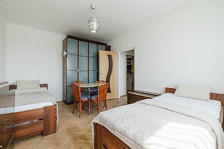 Prostorná ložnice s parketovou podlahou, velká okna, vestavěné skříně a moderní světlé vybavení, ideální pro pohodlné bydlení.