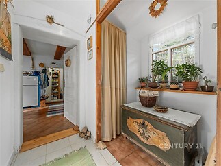 Vstupní chodba s dlažbou a dřevěným truhlou působí rustikálním dojmem, s velkými okny poskytujícími dostatek světla.