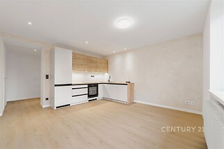 Moderní kuchyň s parketovou podlahou a vestavěnými spotřebiči, světlý interiér s dřevěným dekorem a elegantním designem.