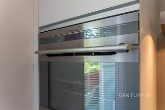 Moderní kuchyň s vestavěnou troubou, nerezové povrchy, světlé okolí