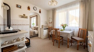 Jídelní kout s dřevěným nábytkem, velká okna, světlý interiér, keramická dlažba, útulný styl, rekreační dům v klidné lokalitě.