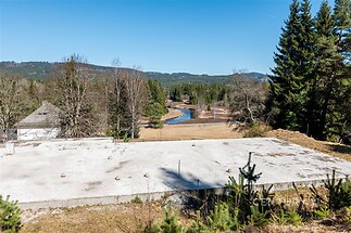 Prázdný stavební pozemek obklopený přírodou a lesy, s výhledem na řeku a kopcovitou krajinu, ideální pro výstavbu rodinného domu