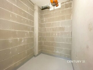 Prázdná sklepní místnost s betonovými stěnami, světlá dlažba, výborný stav, vhodná pro skladování nebo dílnu.