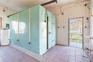 Průmyslový prostor s dlažbou, světlý interiér, velká chladicí jednotka, přístup na venkovní plochu, vhodné pro komerční využití.