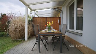 Terasa se vzorovanou dlažbou a zahradním nábytkem nabízí útulné venkovní posezení. Zastřešení zajišťuje ochranu před počasím.