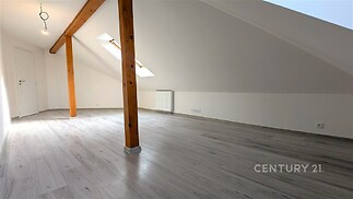 Podkrovní pokoj s moderní laminátovou podlahou, přirozeně osvětlený díky střešním oknům, stylové dřevěné trámy doplňují světlý interiér.