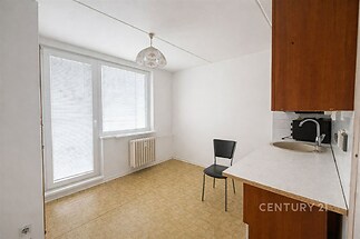 Světlá kuchyň s laminátovou podlahou, velkými okny a vestavěným radiátorem nabízí moderní prostor ideální pro rekonstrukci.