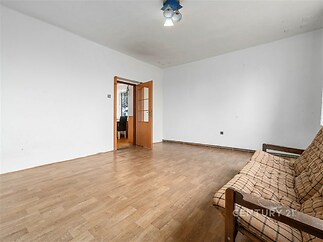 Prostorný obývací pokoj s parketovou podlahou, světlý interiér s dřevěnými dveřmi, vhodný k rekonstrukci.