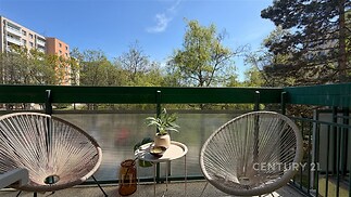 Balkon s moderním designem, dvěmi pohodlnými křesly a stolkem, výhled na zeleň. Podlaha z dlažby, ideální pro relaxaci.