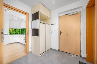 Předsíň s dlažbou, vestavěné skříně, světlý interiér, moderní design, přístup do kuchyně s parketovou podlahou.