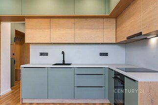 Moderní kuchyň s dřevěnými prvky, světlá parketová podlaha a vestavěné skříně, minimalistický design a integrované spotřebiče.