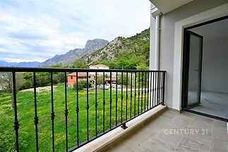 Balkon s dlažbou a kovovým zábradlím nabízí panoramatický výhled na hory a zeleň, ideální pro moderní bydlení s přírodním okolím.