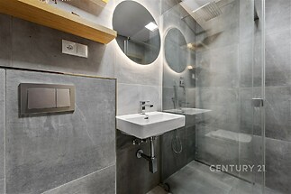 Moderní koupelna s dlažbou, sprchovým koutem a podsvíceným zrcadlem. Elegantní, renovovaný prostor s minimalistickým designem.