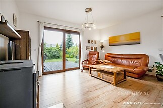 Světlý obývací pokoj s dřevěnou podlahou, velkými okny a moderním nábytkem, ideální pro rodinné setkání.