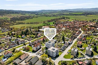 Letecký pohled na rezidenční čtvrť s moderními bytovými domy a zelenými zahradami, v klidné lokalitě s výhledem na okolní krajinu, ideální pro rodiny.