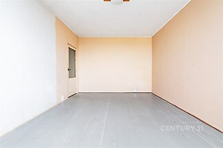 Prázdná místnost s dřevěnou podlahou, vymalovaná v teplých tónech, ideální pro přestavbu či rekonstrukci, nabízí velký potenciál pro využití.