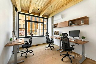 Moderní kancelář s dřevěným stropem, parketovou podlahou a velkými okny, které poskytují dostatek přirozeného světla.