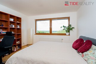 Prostorná ložnice s parketovou podlahou, velkým oknem a moderním nábytkem.