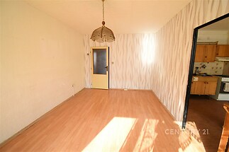 Světlý obývací pokoj s laminátovou podlahou, moderní tapetou a velkým oknem. Propojení s kuchyní pro praktické bydlení.