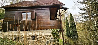 Dřevěná chata s kamenným základem nabízí klidné prostředí v zalesněné oblasti, ideální pro rekreaci a relaxaci mezi stromy.