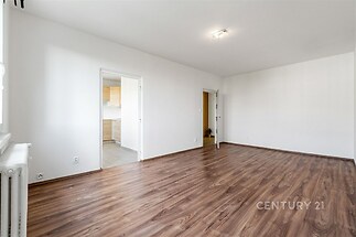 Prostorný obývací pokoj s parketovou podlahou, světlý interiér, moderní design, propojený s kuchyní.