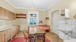 Kuchyň s vintage dřevěným stolem, retro skříňkami a spací částí. S umyvadlem a dlažbou, vytváří rustikální atmosféru, prostorná a světlá.