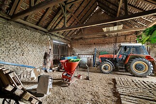 Prostorná stodola s dřevěným stropem a cihlovými zdmi, zemědělské vybavení, dobrý stav, vhodné pro skladování nebo farmářské využití.