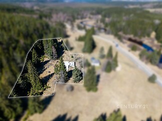 Prázdná stavba a okolní pozemek obklopený lesem, vhodný pro výstavbu.