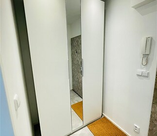 Vstupní hala s vestavěnými skříněmi, dlažbou a moderním osvětlením vytváří světlý a praktický prostor ideální pro uložení věcí
