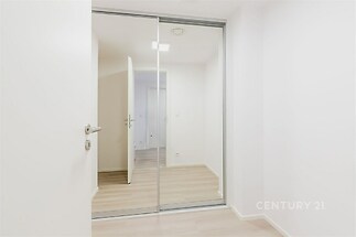 Chodba s vestavěnými skříněmi, moderní interiér, plovoucí podlaha, světlé stěny, elegantní design, ideální pro úložné prostory.