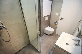 vana s sprcha, skříňka pod dřez, kachličková podlaha, a toaleta